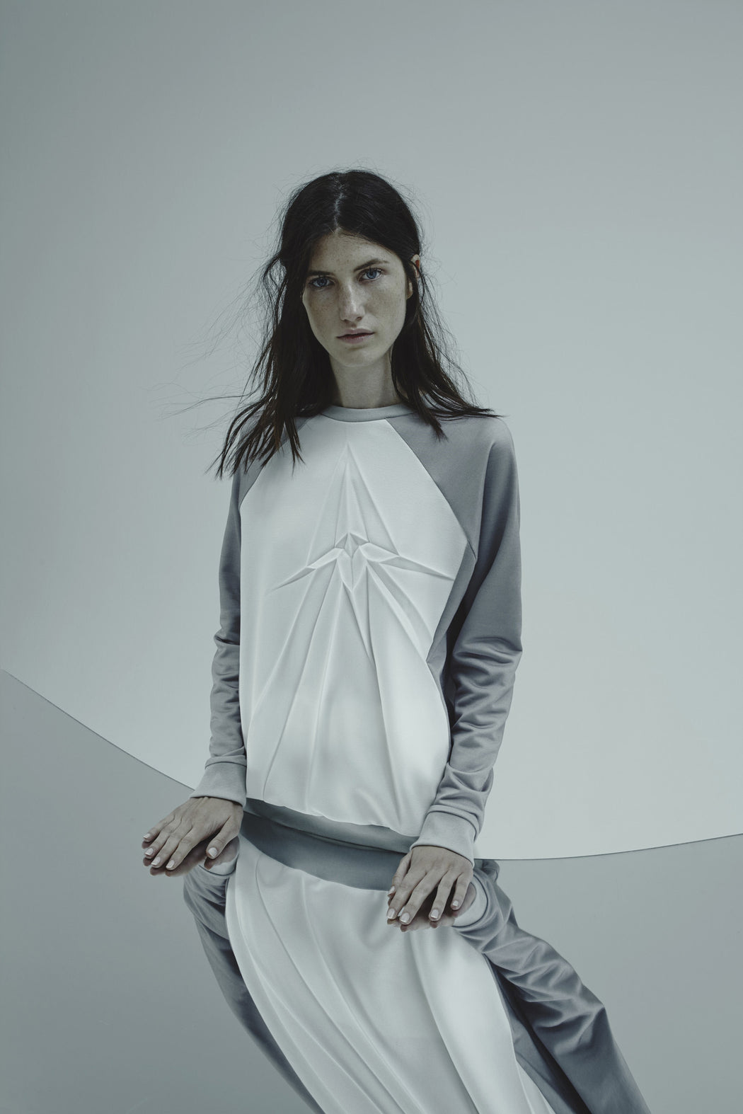 Model wearing white sweatshirt pleated with a crack design on a plain background