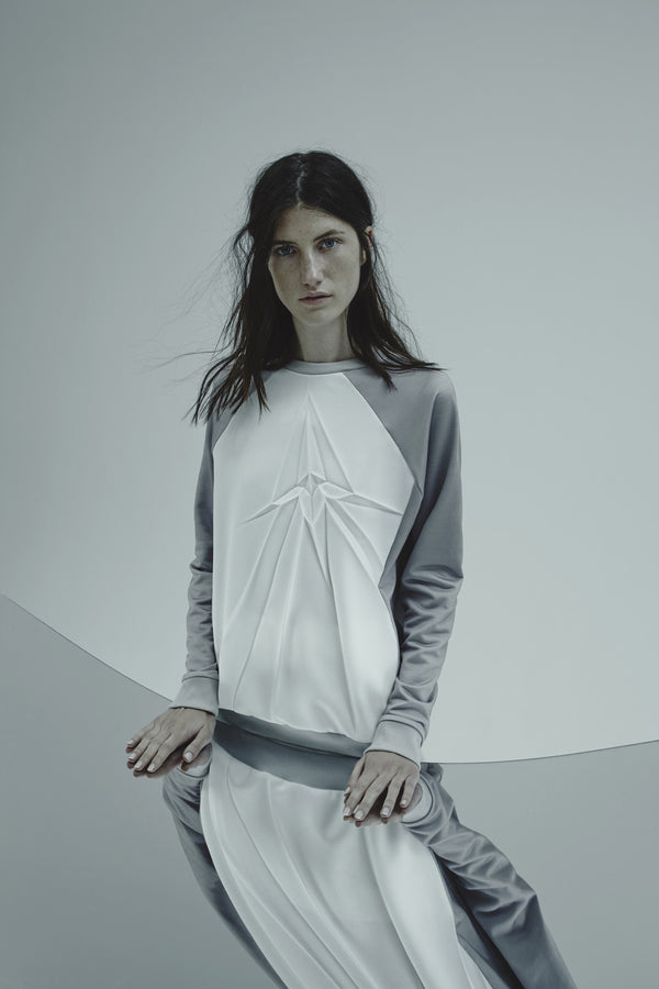 Model wearing white sweatshirt pleated with a crack design on a plain background