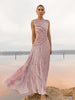 Model wearing a pink sleeveless velvet floor length dress pleated all over in a striking sunray design with side cut out at waist standing on a stone by the river 