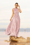 Model wearing a pink sleeveless velvet floor length dress pleated all over in a striking sunray design with side cut out at waist standing on a rock by the river