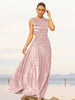 Model wearing a pink sleeveless velvet floor length dress pleated all over in a striking sunray design with side cut out at waist with river as background