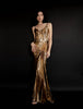 Model wearing a floor length metallic dress with adjustable straps, sunray pleats, a gathered skirt detail, a loose hem on the strapped top, and a flattering draped asymmetric hemline, against a solid black studio background.