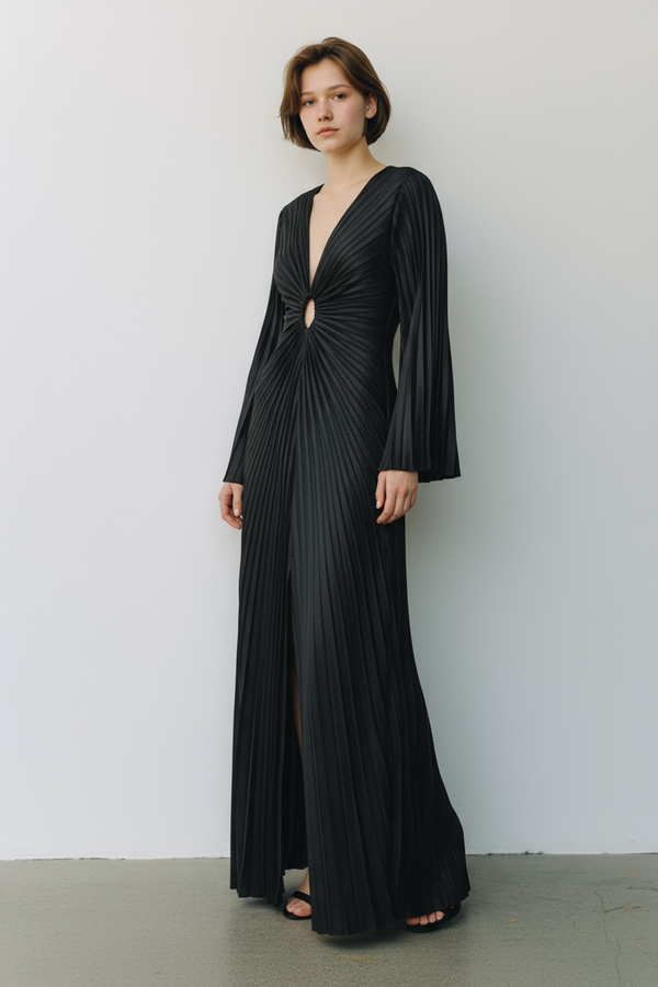 Model wearing a black velvet floor-length gown pleated all over in a striking sunray design with keyhole detail against a white background