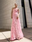 Model in pink sleeveless floor-length dress pleated in a sunray pattern with French baroque style lace standing against a light-colored building
