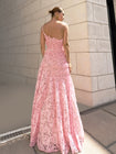Model in pink sleeveless floor-length dress pleated in a sunray pattern with French baroque style lace standing against a light-coloured brick wall.