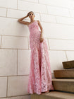 Model in pink sleeveless floor-length dress pleated in a sunray pattern with French baroque style lace standing on steps with a light-colored wall background